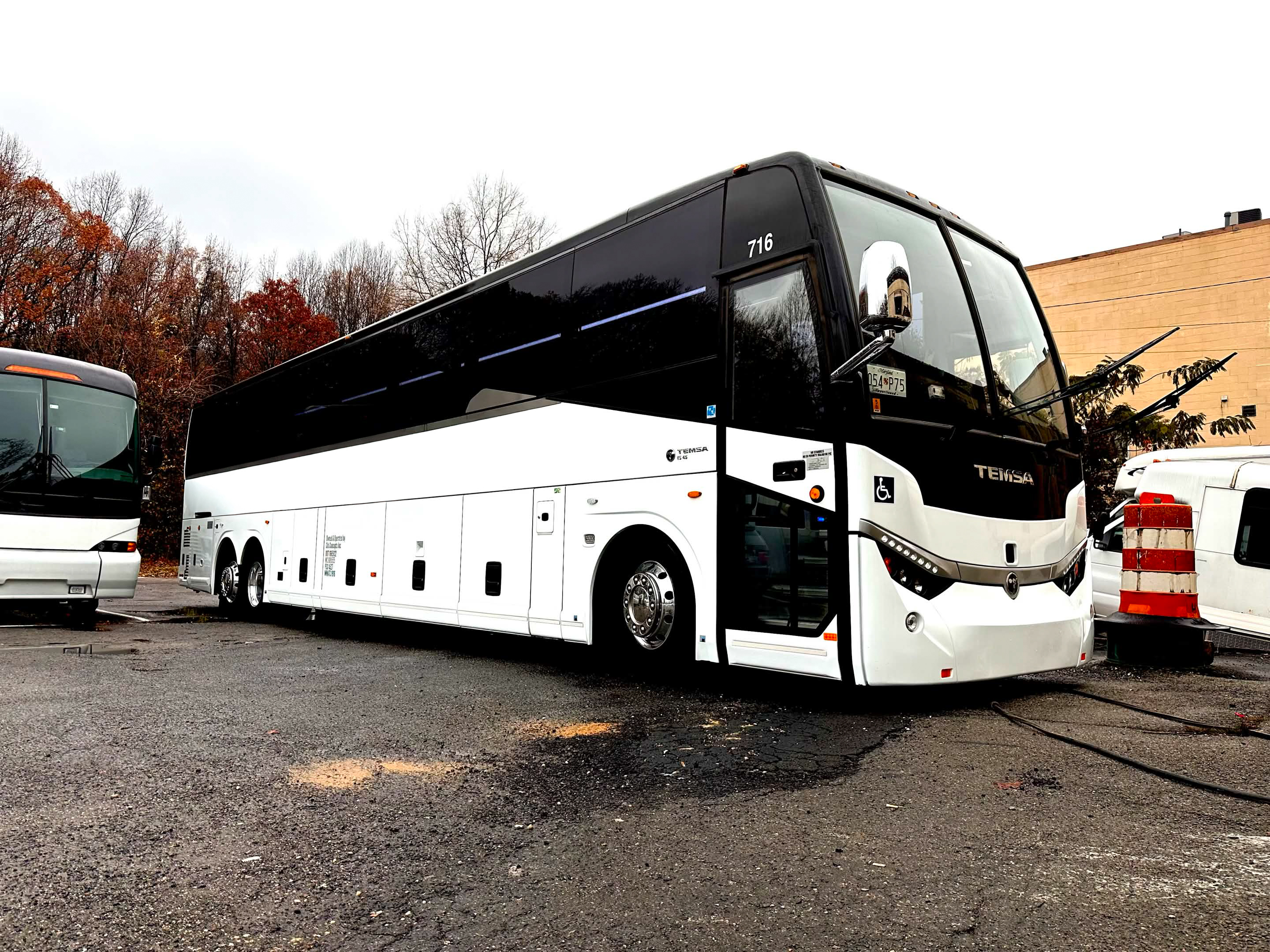Full-size white and black Temsa motorcoach bus shown from the front-right with entry door and accessibility lift