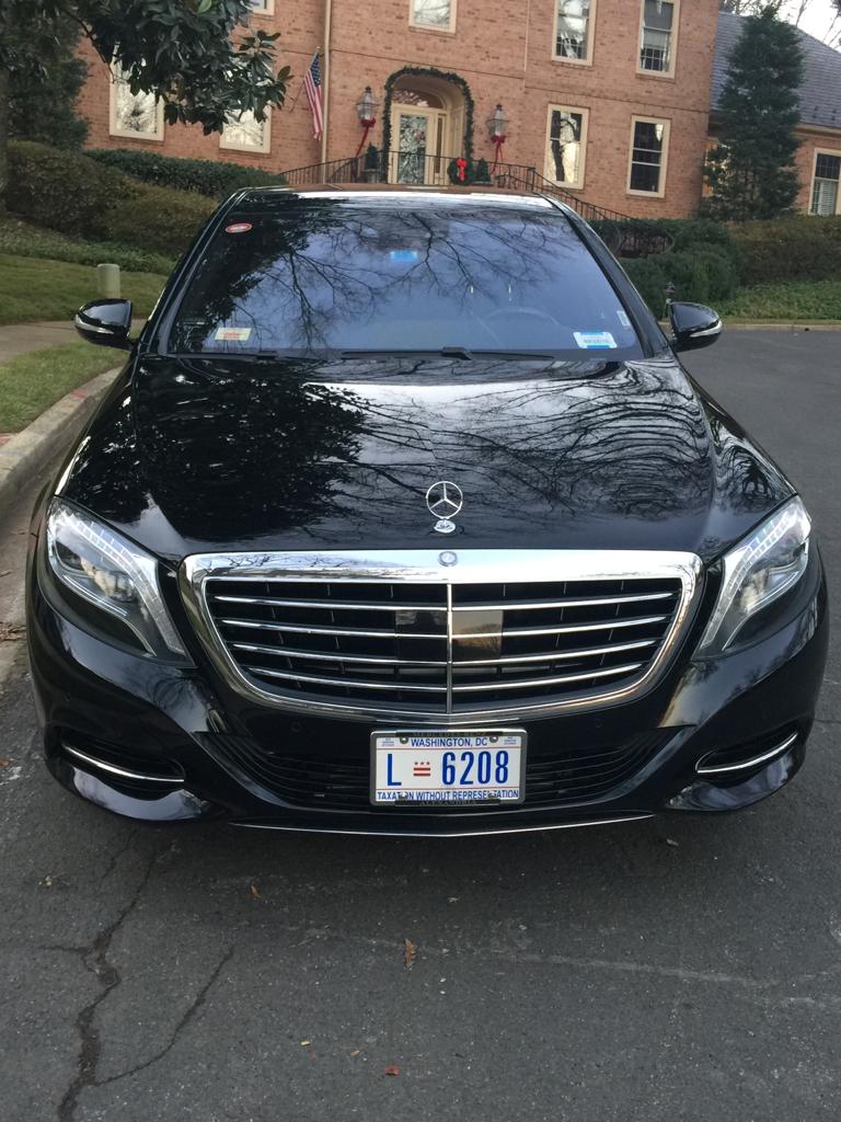 Black Mercedes-Benz S-Class sedan parked in front of a brick home in Washington, D.C.
