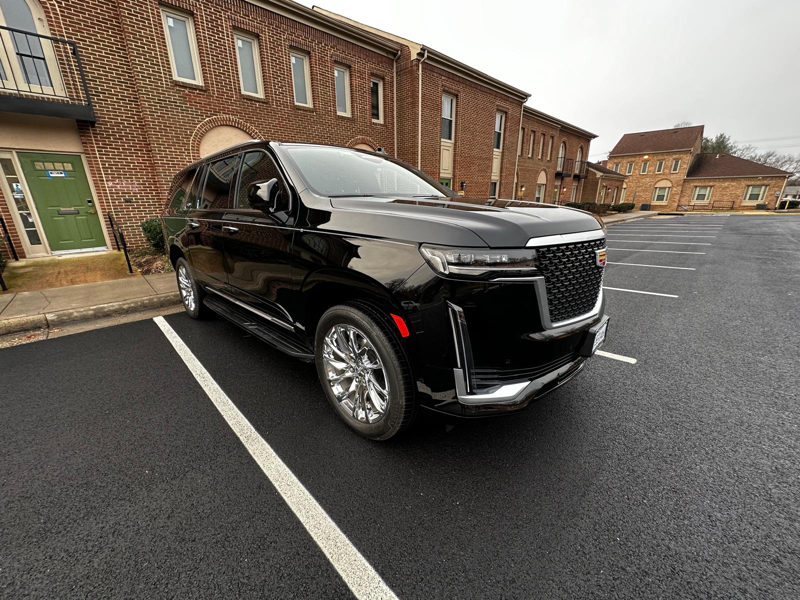 Black Cadillac Escalade ESV parked outside a brick building